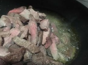 油烧热后倒入牛肉条中小火翻炒一会儿加入盐继续翻炒。