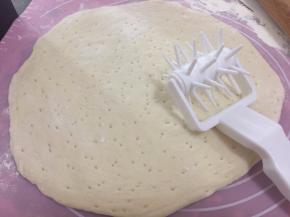 在案板上撒了面粉，取出面团擀圆，然后用滚针在面皮上滚一滚