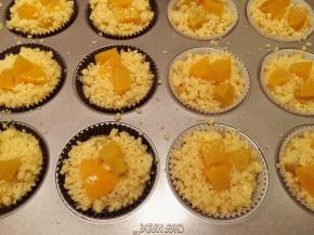 装入裱花袋挤入已经放好纸托的模具内，大概八分满，放上酥粒，摆放剩余的黄桃粒