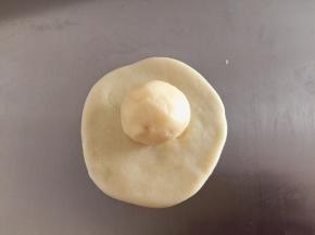 分别取一小份水油皮和油酥皮，水油皮面团擀平，包住油酥面团