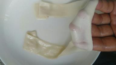 醒好的面片，按扁，拉起两端，抻出非常薄而长的面条。