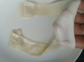 醒好的面片，按扁，拉起两端，抻出非常薄而长的面条。