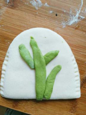 绿色面团取一点搓成长条并摁扁，抹少许水固定在口袋饼上，做成树干的形状，这个可以随意做成自己喜欢的任何形状