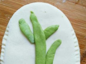 绿色面团取一点搓成长条并摁扁，抹少许水固定在口袋饼上，做成树干的形状，这个可以随意做成自己喜欢的任何形状