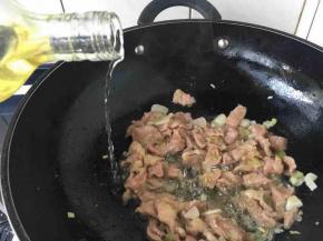 翻炒后肉片迅速变白，马上沿锅边倒入少许料酒。
