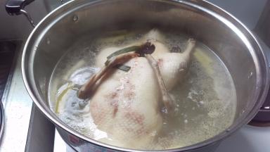 葱切小段，姜切片。把全鸭去水后烧一锅葱姜水（1/2姜和葱），煮沸以后加入鸭子，等到水沸腾后换中火煮50分钟。中间翻身1次（因为水盖不住全鸭子）。