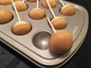 棒棒糖出炉马上脱模，一个个分别插入巧克力液内，均匀地沾上巧克力液放凉