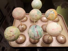 棒棒糖蛋糕插入彩色巧克力液内，轻一圈后提起插在模具上放凉