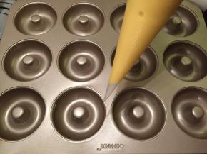 12连甜甜圈冼净擦干，轻轻涂抺上一层薄薄的黄油。蛋糕液装入裱花袋
