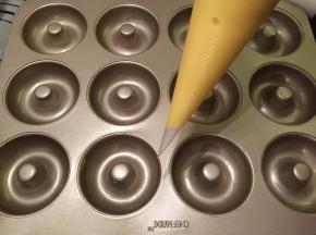 12连甜甜圈冼净擦干，轻轻涂抺上一层薄薄的黄油。蛋糕液装入裱花袋