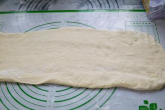 在案板上撒面粉，把面团稍擀成长方形