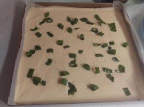 再放上去葱和芝麻。放入烤箱烤15分钟 ，出炉后马上倒扣，把后面的油纸撕掉，马上涂上沙拉酱和肉松，靠身体这个位置要涂多点，厚点，然后马上卷，这样不容易开裂。卷好以后放冰箱30分钟，就可以固定蛋糕卷咯！