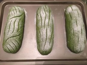 取出面包胚，烤箱预热180度。均匀地在面包胚上筛上干粉，用刀片随意在面包上割出喜欢的花纹