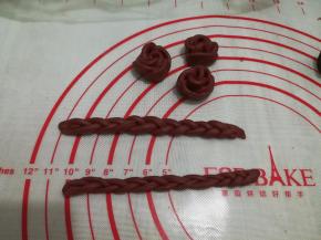 加了红曲粉的面团做了3朵玫瑰花和两个小辫子，用保鲜膜盖好，等待南瓜面包发酵至1.5倍大（造型可按个人喜好）