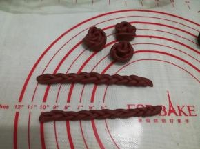 加了红曲粉的面团做了3朵玫瑰花和两个小辫子，用保鲜膜盖好，等待南瓜面包发酵至1.5倍大（造型可按个人喜好）