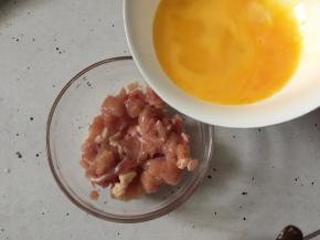 将鸡腿肉去骨切丁后放入碗里加入盐，然后分多次少量加入打散的鸡蛋液向一个方向搅拌上劲