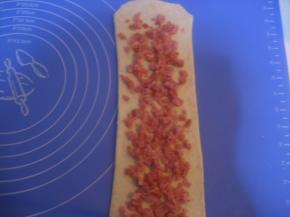 翻面，擀长；在表面撒上适量火腿丁；