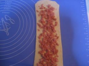 翻面，擀长；在表面撒上适量火腿丁；