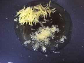 酸菜水份炒干后装碗备用，锅里倒入适量油爆香蒜末和姜丝