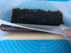 擀面杖放在靠近身体的一侧油纸下面。