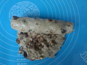 将有果料的面团擀成椭圆形，撒上一层红糖，自上而下卷起，捏紧。