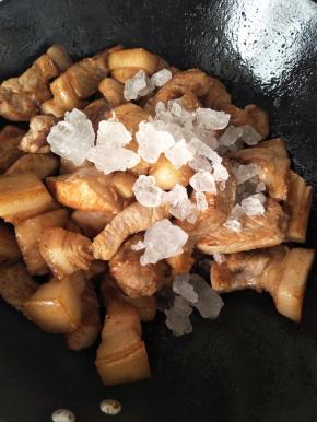 将肉放到炒锅中加入冰糖，翻炒一会，炒至糖几乎融化，肉开始变色