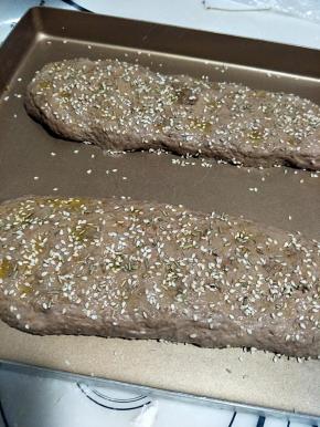 松弛好后， 用手指在面团表面戳一排，然后刷上橄榄油，看自己的喜欢，撒上香草和芝麻。