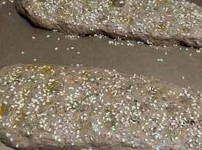 松弛好后， 用手指在面团表面戳一排，然后刷上橄榄油，看自己的喜欢，撒上香草和芝麻。