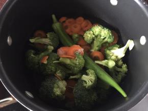 将西兰花、胡萝卜薄片、甜玉米粒、秋葵放入开水锅中加入适量盐和油焯熟