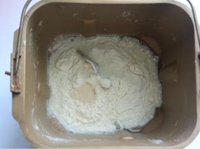 将披萨皮的所有材料放入面包桶里，酵母放在最上面，面粉挖个洞放入酵母再用面粉盖住
