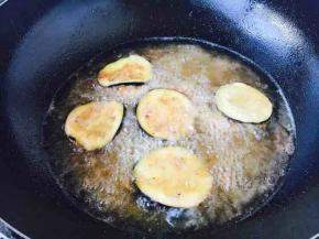 当茄盒从油中浮起时用长筷子将茄盒翻一个个，当看到茄盒略有金黄色时捞出沥油备用。其它的茄盒也是如此炸制。