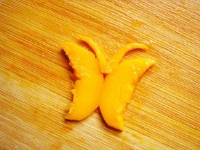 小蝴蝶制作：取两片小点的芒果片背对着放，切两个小细条做触须，摆放到中间即可。