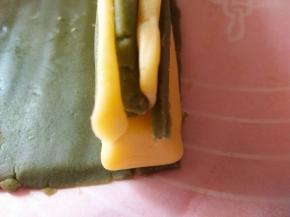 将抹茶面团切3个0.6CM宽的长条，依次叠起来放在兔兔脸的上方（垫油纸压实，防止有空间）两个耳朵分别放两侧（压实）抹茶面团再切出2个0.3CM的长条放在耳朵两侧（压实）