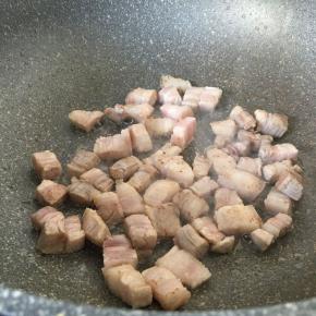 五花肉下锅炒至微黄，加少许料酒和半汤匙生抽。