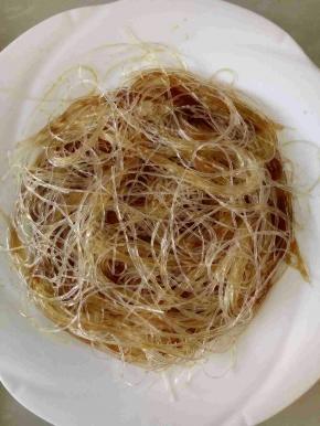 粉丝沥干水份加入蒸鱼豉油和生抽拌匀，铺入盘内