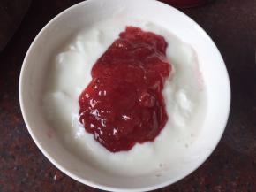 将酸奶和草莓果酱勺入碗里