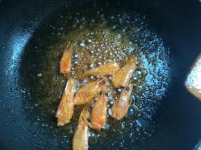 下入鲜虾头，一遍翻炒一般压挤虾头，煸出红油，捞出不用。