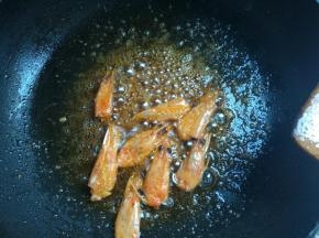 下入鲜虾头，一遍翻炒一般压挤虾头，煸出红油，捞出不用。