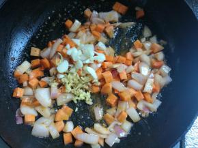 接着放入红萝卜丁，翻炒两下，放入蒜片姜末翻炒均匀。