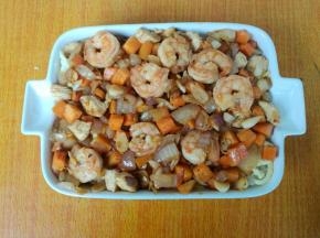 把炒好的鲜虾铺在焗饭盘。