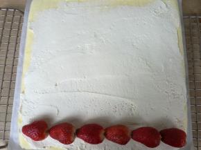 用抹刀把打发好的奶油平铺在蛋糕体上，（留一点奶油用在蛋糕表面），放上洗净晾干的草莓。