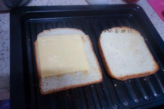 取出吐司翻面放上两片芝士片，烤5分钟芝士融化即可