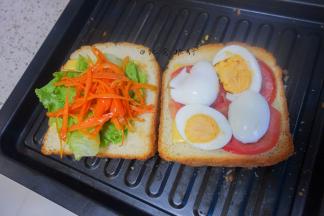 将番茄片、水煮蛋片、生菜一层一层码在面包上