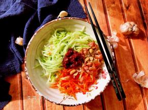 捞出面条淋干水分放在碗底，上面铺上黄瓜丝和胡萝卜丝、花生碎，再放适量辣酱。