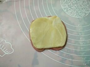 （7）将第二次擀卷的成品，用拇指在中间压一下，用虎口位置把卷对夹起来，对夹方向朝上，用手摁扁，再用擀面杖擀成边缘薄、中间厚的圆饼。