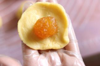 9取一个饼皮按扁，放入1个馅料，类似蛋黄酥的包法。