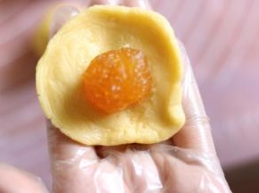 9取一个饼皮按扁，放入1个馅料，类似蛋黄酥的包法。