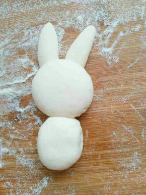 小兔子耳朵抹少许水沾在兔子头合适的位置，然后再拿小块面团捏成长方形做兔子的身体，抹水固定好