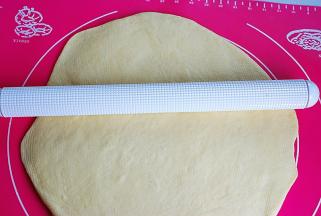 4.把面团取出，放案板上按扁，用排气棒将气体均匀的排出