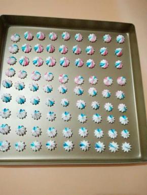 4、用牙签蘸取少量的色素，涂抹在裱花袋里，然后装入蛋白糊，挤在烤盘上，这时预热烤箱100度10分钟。